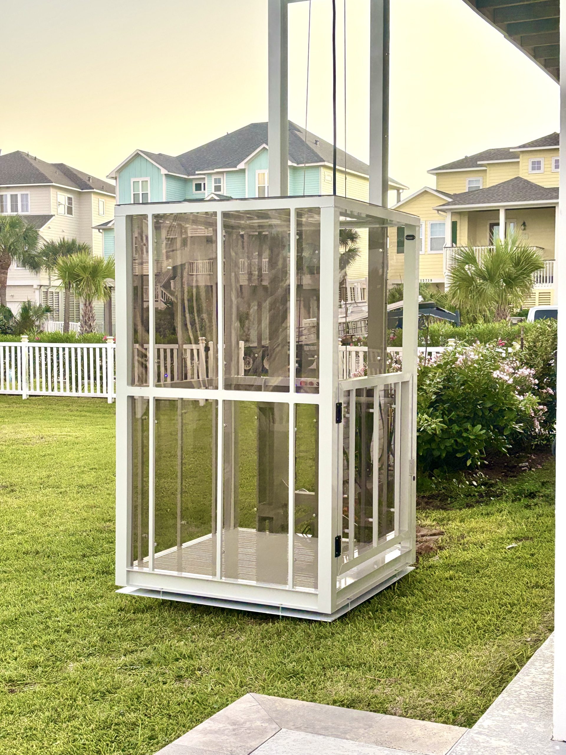 Galaxy Traveler passenger platform lift beside a row of colorful pastel beach houses and palms