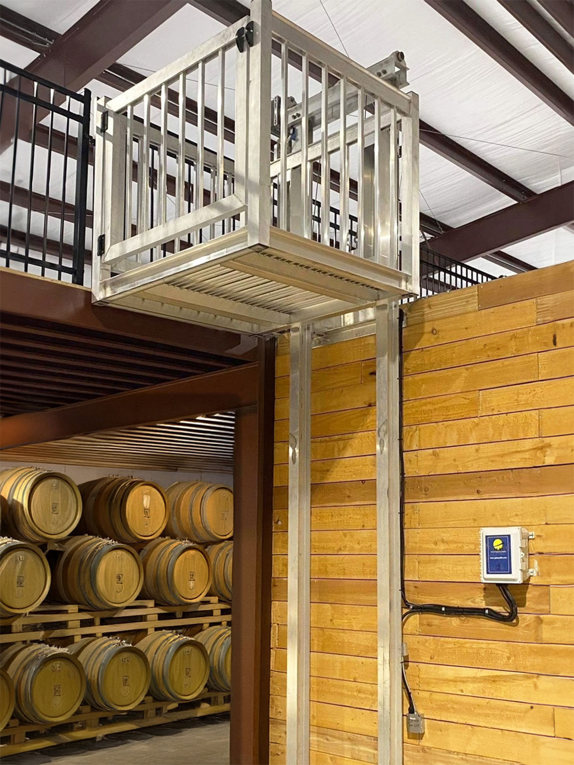 Galaxy Voyager+ cargo lift raised to a mezzanine above stacked barrels in a winery interior